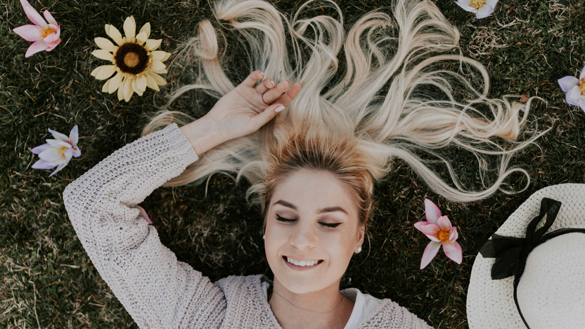 A Happy Woman Lying On The Grass With Flowers